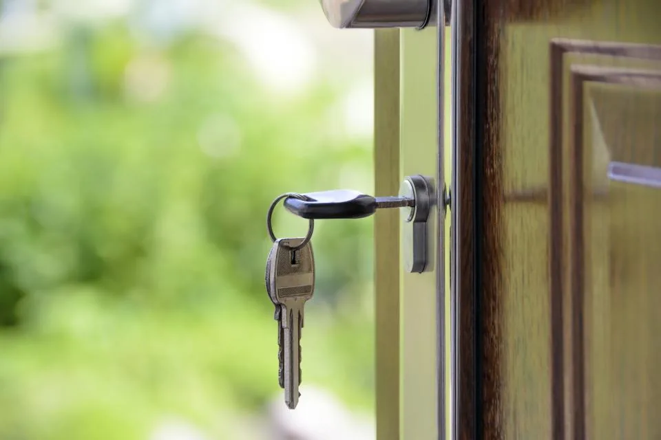 A set of keys in the lock of an open front door